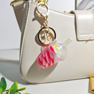Pink pearl milk tea sundae keychain with golden link on a stylish white handbag