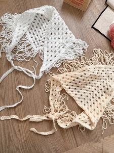 Detail of crochet knit bandanas in white and beige with mesh pattern and fringe