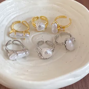 Elegant gold and silver irregular baroque pearl rings with zircon in a ceramic dish