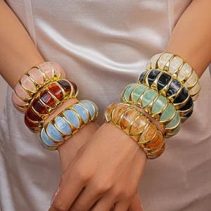 Close-up of colorful resin acrylic bangles with metal edges worn by a model