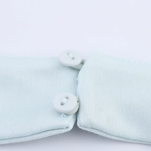 Dettaglio dell'abito in maglia azzurro con texture a costine e due bottoni bianchi