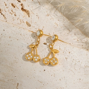 Gold cherry stud earrings with rhinestones on a natural stone background