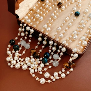 Detail of layered tiger eye and pearl necklace displayed on a vintage jewelry box