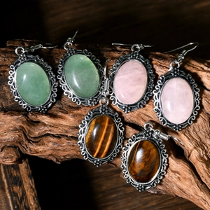 Close-up of vintage hollow silver earrings with pink crystal and tiger eye stones