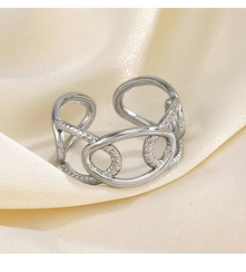Détail d'une bague argentée ajustable à lignes évidées sur fond de satin crème