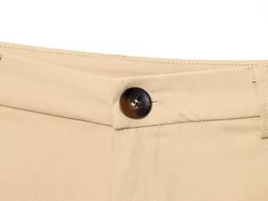 Detail of khaki trousers waist with a dark marble button and fine twill fabric texture