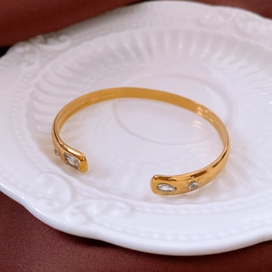 Detailed macro view of gold-plated bangle with sunburst engravings and zircon settings