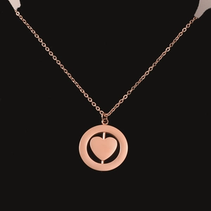 Detail of a rose gold dual-layer necklace with a rotating heart and circular pendant
