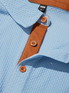 Détail du polo bleu pour hommes avec texture gaufrée et patte de boutonnage orange