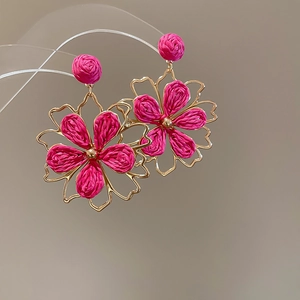 Detailaufnahme der handgefertigten goldgeränderten rosa Bast-Blütenohrringe