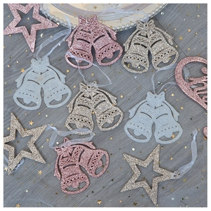 Close-up of pink and silver glitter bell and star ornaments on gray wooden background
