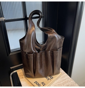 Detail of dark brown leather tote bag with vertical pockets on a marble surface