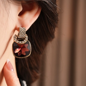 Close-up of vintage square red crystal earrings with diamond-encrusted gold settings