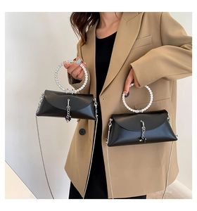 Detail of black trapezoid bag with rhinestone ring handle and silver chain strap