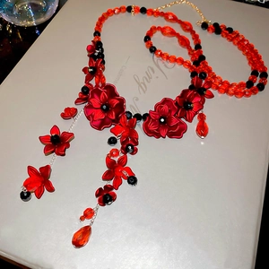 Detaillierte Makroansicht roter Acrylblüten und facettierter Perlen an einer Taillenkette