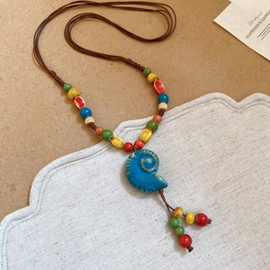 Dettaglio di un ciondolo a conchiglia blu su una collana bohémien con perline colorate