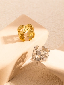 Macro detail of gold and silver ginkgo leaf rings on a stone pedestal display