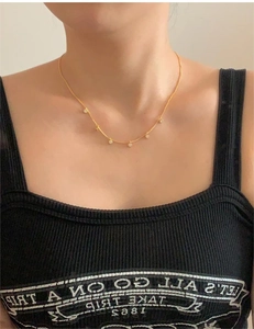Detailed view of a gold dainty chain necklace featuring five delicate round white pearls