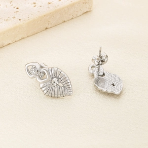Detailed view of silver heart-shaped stainless steel earrings with radial texture and diamonds