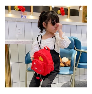 Toddler wearing a cute red dinosaur canvas backpack with a yellow crown decoration
