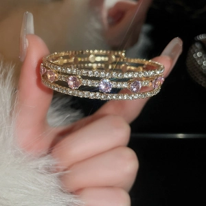 Macro detail of multilayer gold zircon bracelet featuring pink purple gemstone accents