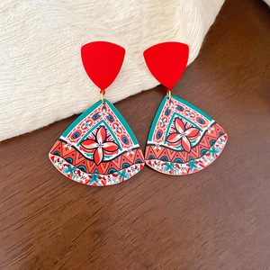 Close-up of bohemian acrylic earrings with complex geometric floral prints on wood background
