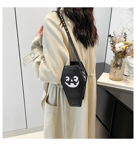 Side view of a black coffin-shaped crossbody bag with a white Halloween pumpkin face print