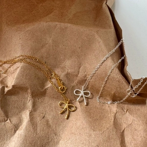 Detailed close-up of delicate bow pendant necklaces in gold and silver finish