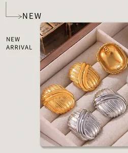 Detail of vintage textured gold and silver oval earrings on a wooden jewelry display