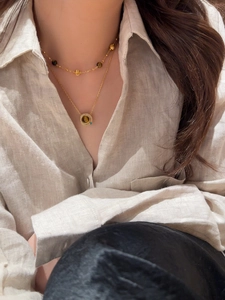 Détail d'un collier multicouche plaqué or 18 carats avec pendentif œil de tigre sur modèle