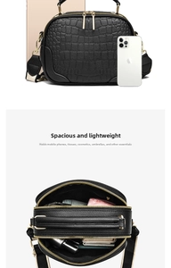 Detail view of black crocodile pattern crossbody bag with wide strap and dual zippers