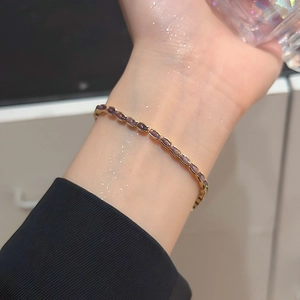 Detailed close-up of an elegant gold bracelet with oval purple zircon gemstones