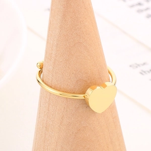 Minimalist gold heart-shaped open ring on a wooden stand with a warm background