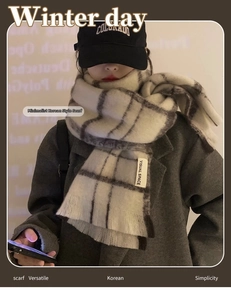 Detail of grey plaid scarf with fringes and woven brand label in a winter look