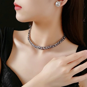 Close-up of model wearing black stone tennis necklace and white crystal stud earrings