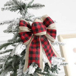 Christmas buffalo plaid and burlap ribbon bow ornament on a snow-covered tree