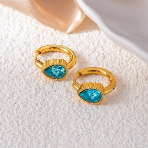 Close-up of teardrop blue crystal earrings with vintage gold-tone textured metal bands
