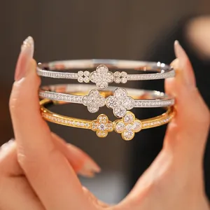 Sparkling zircon clover charm bracelets in silver and gold tones held by a model