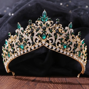 Detailed close-up of a gold luxury bridal crown with green and clear crystals on wood