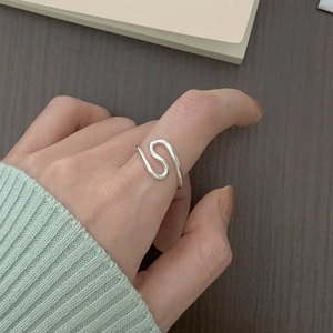 Detail of minimalist 925 sterling silver wavy open ring on a female finger
