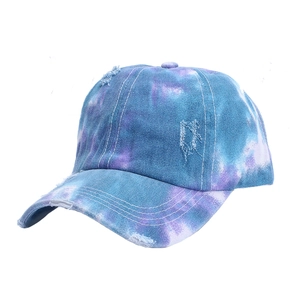 Dettaglio del cappellino tie-dye invecchiato con bordi sfilacciati e trama denim viola