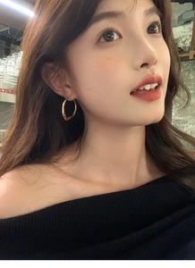 Close-up of minimalist golden irregular hoop earrings worn by a model in soft lighting