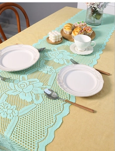 Detail of mint green lace table runner with hollow rose pattern and wavy edges