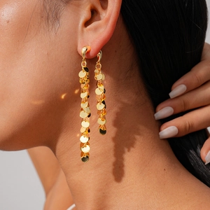 Vue macro de boucles d'oreilles pendantes en or 18k avec sequins ronds sur mannequin