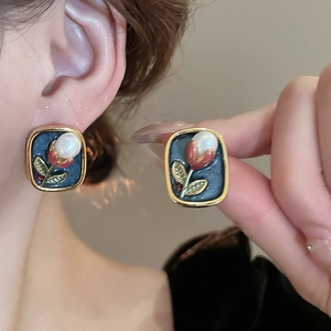 Close-up of vintage blue square earrings with red tulip design and pearl accents