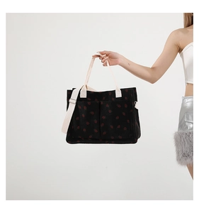 Detail of black corduroy tote bag featuring strawberry prints and dual front pockets