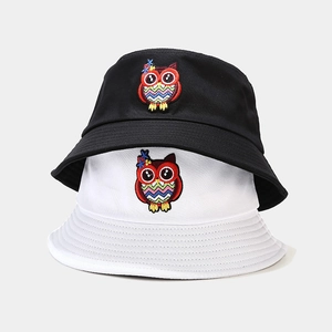 Close-up of colorful owl embroidery and parallel stitching on black and white bucket hats