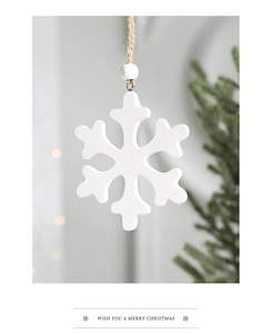 Close-up of white wooden snowflake ornament with jute rope and beads on a festive background