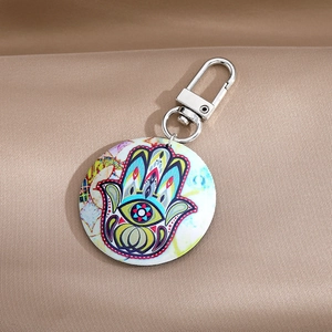 Bohemian Hamsa Hand and Evil Eye round keychain with silver metal clip on silk background