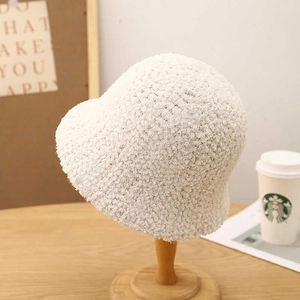 Winter fluffy faux fur bucket hat in cream white displayed on a wooden stand